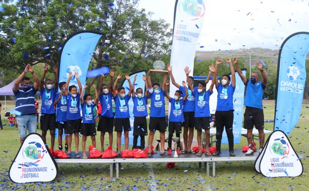 Quinze joueurs de la Ligue Réunionnaise Football à La Danone Nations Cup fêtent la collecte de 14 tonnes de denrées alimentaires sur un podium 
