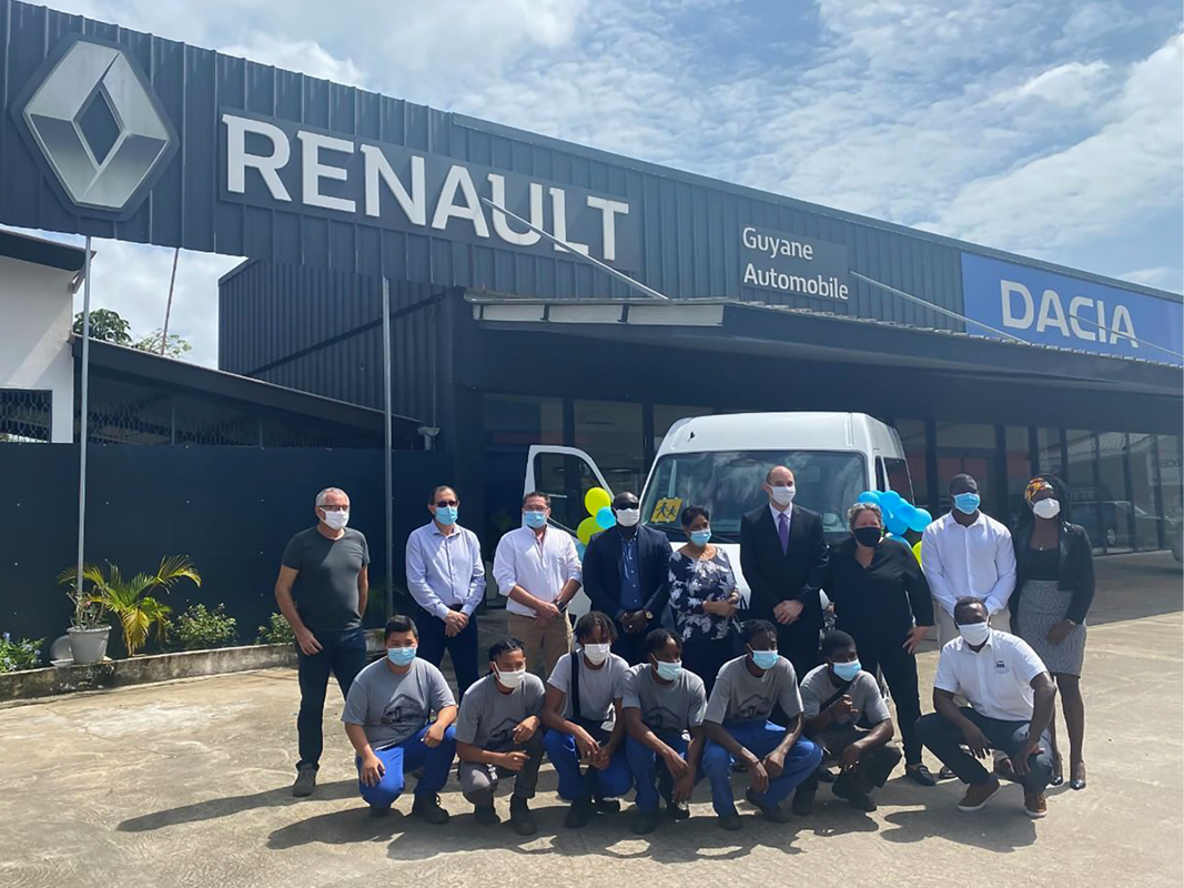 Group of young people in vocational training and employees of Guyane Automobile in front of the sign